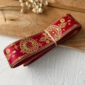 Macro shot of red ribbon roll with gold foil magic circle and star patterns for DIY crafts