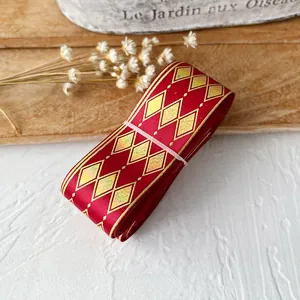 Close-up of red satin ribbon with golden diamond pattern and polka dot decorations