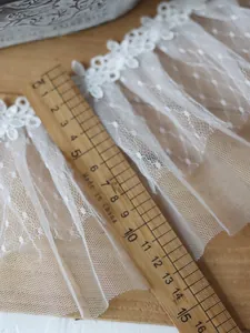 Detailaufnahme von 13cm breiter weißer Spitze mit Lineal zur Anzeige der Stickerei