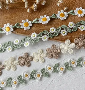 Detail of diverse floral lace embroidery ribbons including daisies on rustic wooden background