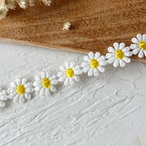 Detailed macro view of white and yellow daisy floral lace trim embroidery on a textured surface