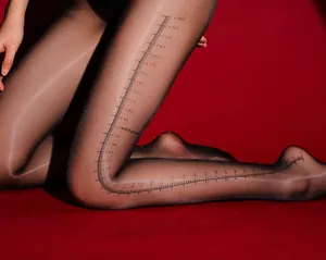 Detail einer schwarzen transparenten Strumpfhose mit weißem Lineal-Aufdruck und Logo