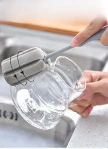 Close-up of long handle sponge brush cleaning the inner base of a glass carafe