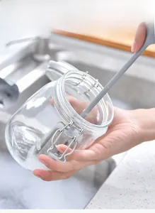 Long handle sponge brush cleaning the bottom of a deep glass bottle in a kitchen