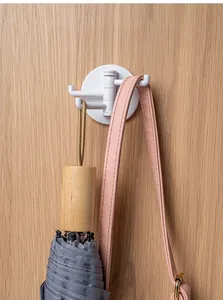 White 4-prong rotating wall hook holding an umbrella and bag on a wooden wall surface