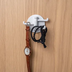 Rotating multi-arm kitchen hook in white plastic mounted on wood wall for small accessories