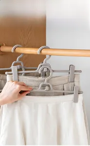 Space-saving stackable pants hanger with adjustable clips shown in a home wardrobe setting