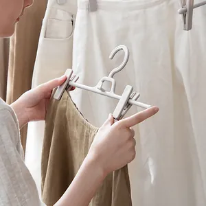 Space-saving grey plastic pants hanger with adjustable clips holding a brown skirt
