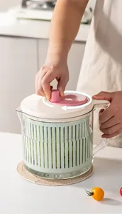 Close-up of manual salad spinner with scale marks and rotating handle in a bright kitchen