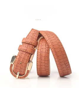Detail of brown crocodile pattern belt with a polished gold alloy buckle and fine stitching