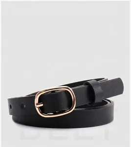 Détail d'une ceinture fine en cuir noir avec une boucle ovale en métal doré