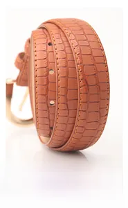 Detail of orange-brown crocodile embossed PU leather belt with smooth oil edge and gold buckle