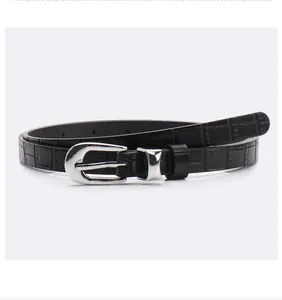 Detail of black faux leather belt with crocodile texture and silver metal buckle