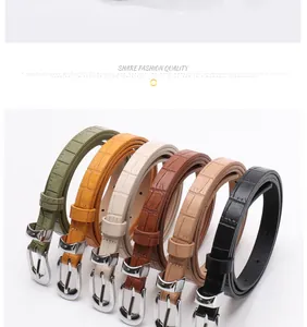 Close-up of thin faux leather belts with stone texture and polished silver metal buckles