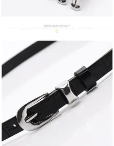 Detail of black faux leather belt with crocodile texture and silver metal buckle
