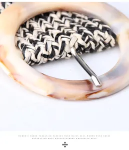 Dettaglio macro di cintura intrecciata boho con fibbia rotonda in resina ambra e fibre intrecciate