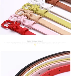 Detail of slim faux leather belt featuring a chic daisy flower buckle in multiple pastel colors