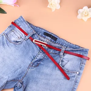 Ceinture fine en cuir rouge pour femme avec boucle dorée sur un jean bleu délavé