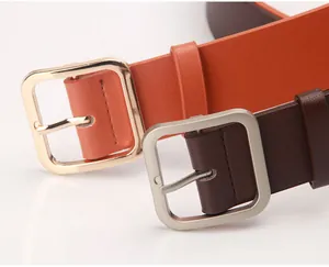 Close-up of minimalist square metal buckles on orange and dark brown PU leather belts