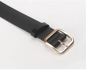 Detail of a black PU leather belt featuring a polished gold square metal buckle