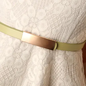 Slim matcha green PU leather belt with square rose gold buckle on white lace dress
