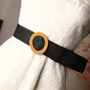 Women's black woven elastic waist belt with round wooden buckle on white lace dress