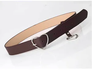 Detail of dark brown leather belt featuring a matte silver heart buckle and pendant