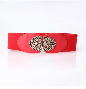Detail of red elastic waist belt featuring a vintage style gold filigree metal buckle