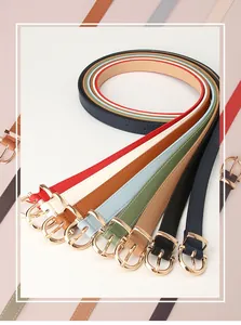 Détail de fines ceintures de mode colorées avec d'élégantes boucles en métal doré pour femme