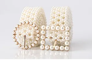 Detail view of woven pearl waist belts with elegant gold round and square buckles