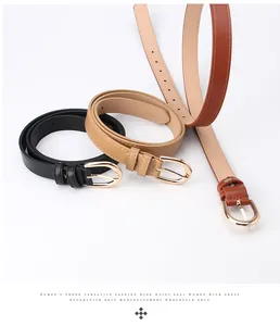 Detail of three slim faux leather belts in black, brown, and khaki with gold buckles