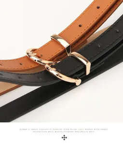 Gros plan sur des ceintures fines en cuir avec boucles dorées rondes en noir et marron