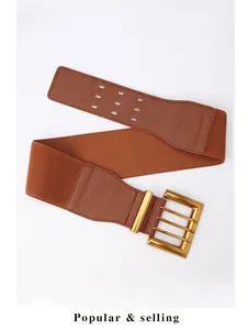 Detail of wide elastic brown belt with triple gold buckle and lychee texture trim