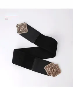 Close-up of vintage engraved gold buckle on elastic black wide waist belt for women