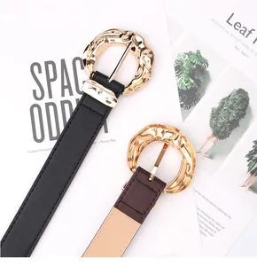 Detalle de cinturones con hebillas doradas martilladas en cuero negro y marrón