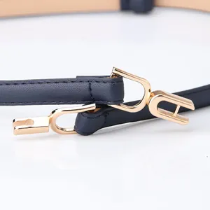 Slim navy blue leather waist belt for women with interlocking gold metal buckle on white