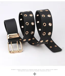Close-up of black faux leather belt featuring double-row gold grommets and a square buckle
