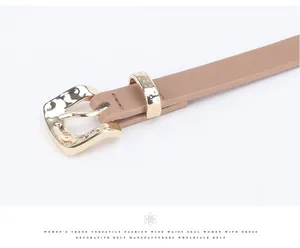 Close-up of a slim khaki leather belt with a hammered texture golden metal buckle