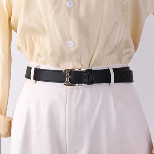 Women's minimalist black leather belt with silver cat-eye buckle on white trousers