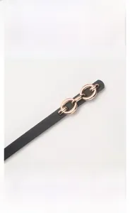 Close-up of elegant gold alloy buckle on a black leather skinny belt for women's dresses
