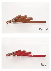Close-up of women's thin PU leather belts in camel and red with gold chain buckle
