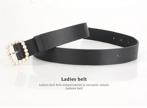 Close-up of black leather belt with golden square buckle featuring elegant pearl inlay