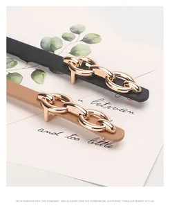 Detail of elegant black and tan leather hair clips with golden interlocking metal links