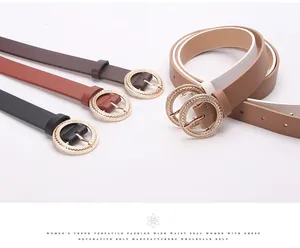 Detail of round golden buckle with woven texture on minimalist faux leather belt