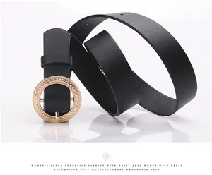 Detail of black leather waist belt with gold round buckle and intricate woven metal texture