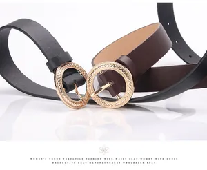 Close-up of black and brown leather belts with round textured golden metal buckles