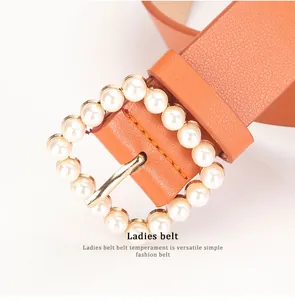 Close-up of caramel leather belt featuring a square buckle with elegant pearl inlay