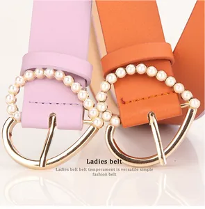 Macro shot of stylish leather belts with heart-shaped gold buckles and white pearls