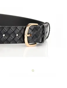 Gros plan sur une ceinture en cuir tressé noir avec une boucle ardillon dorée en alliage