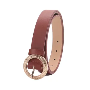 Brown slim leather belt for women with textured golden round buckle on white background